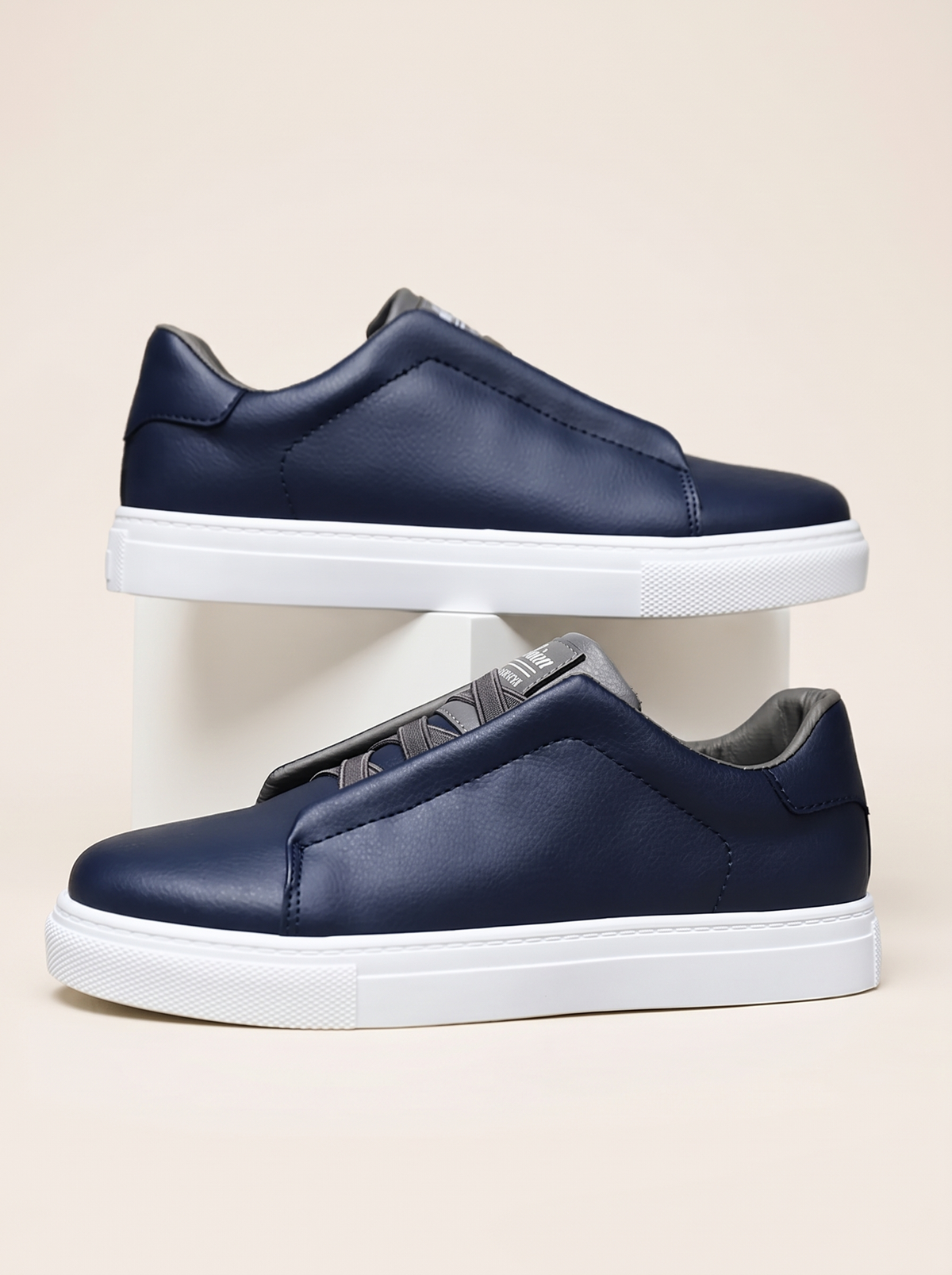 Pair of navy slip-on low-top sneakers with grey elastic panel and white cupsole, side profile