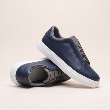 Navy slip-on low-top sneakers angled to show the grey elastic panel and grey lining